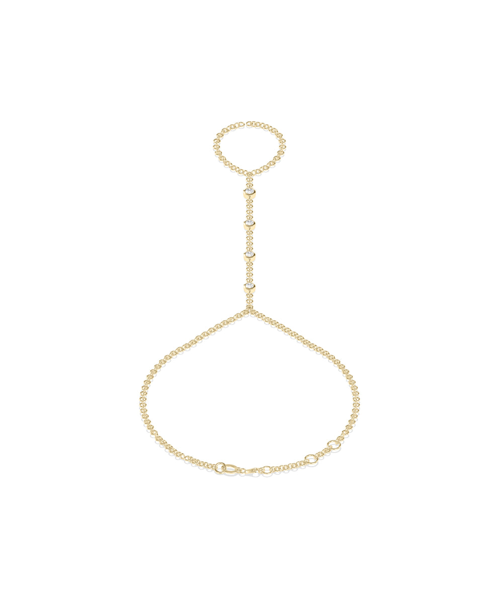 14k yellow gold hand chain with bezel-set diamonds connecting a finger ring to a wrist bracelet