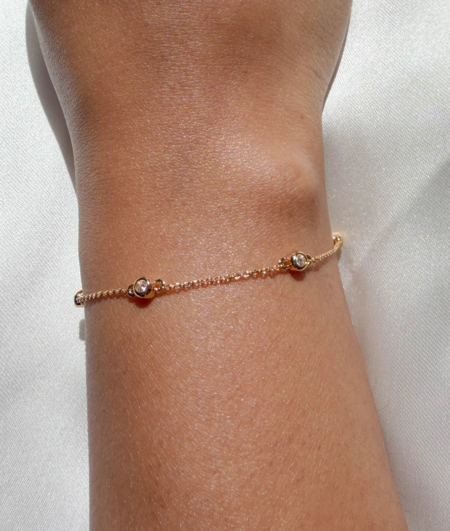 Model wearing yellow gold bezel set diamond station bracelet