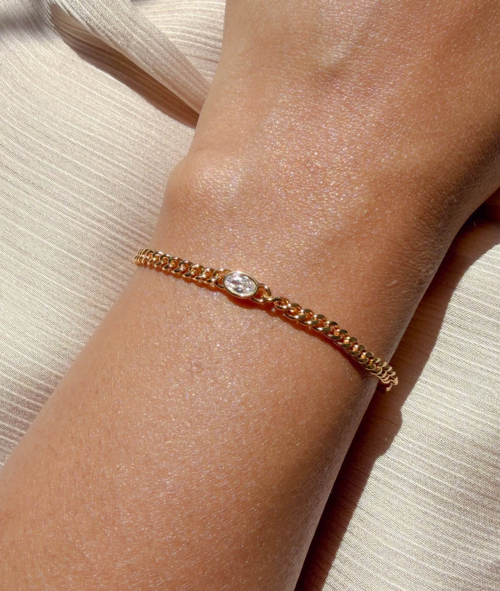 Model wearing diamond solitaire curb link bracelet in yellow gold