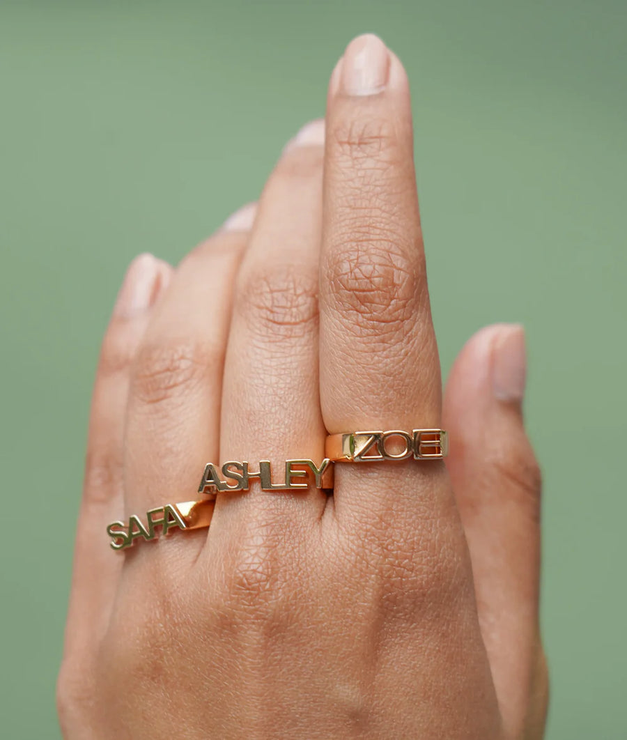 Model wearing personalized gold initial band ring in yellow gold