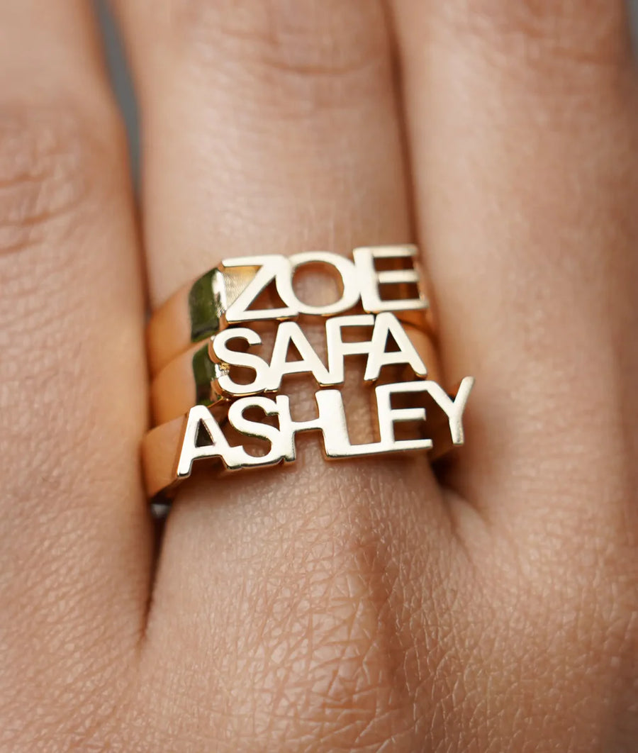 Model wearing three personalized gold initial band rings on finger