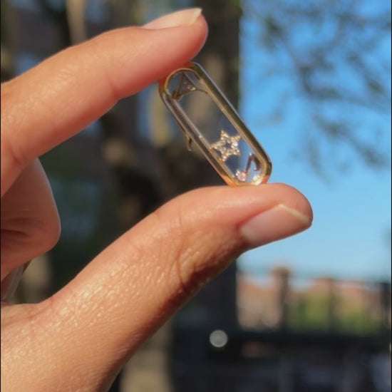 Capsule glass locket charm styled with layered chains and mixed pendant shapes