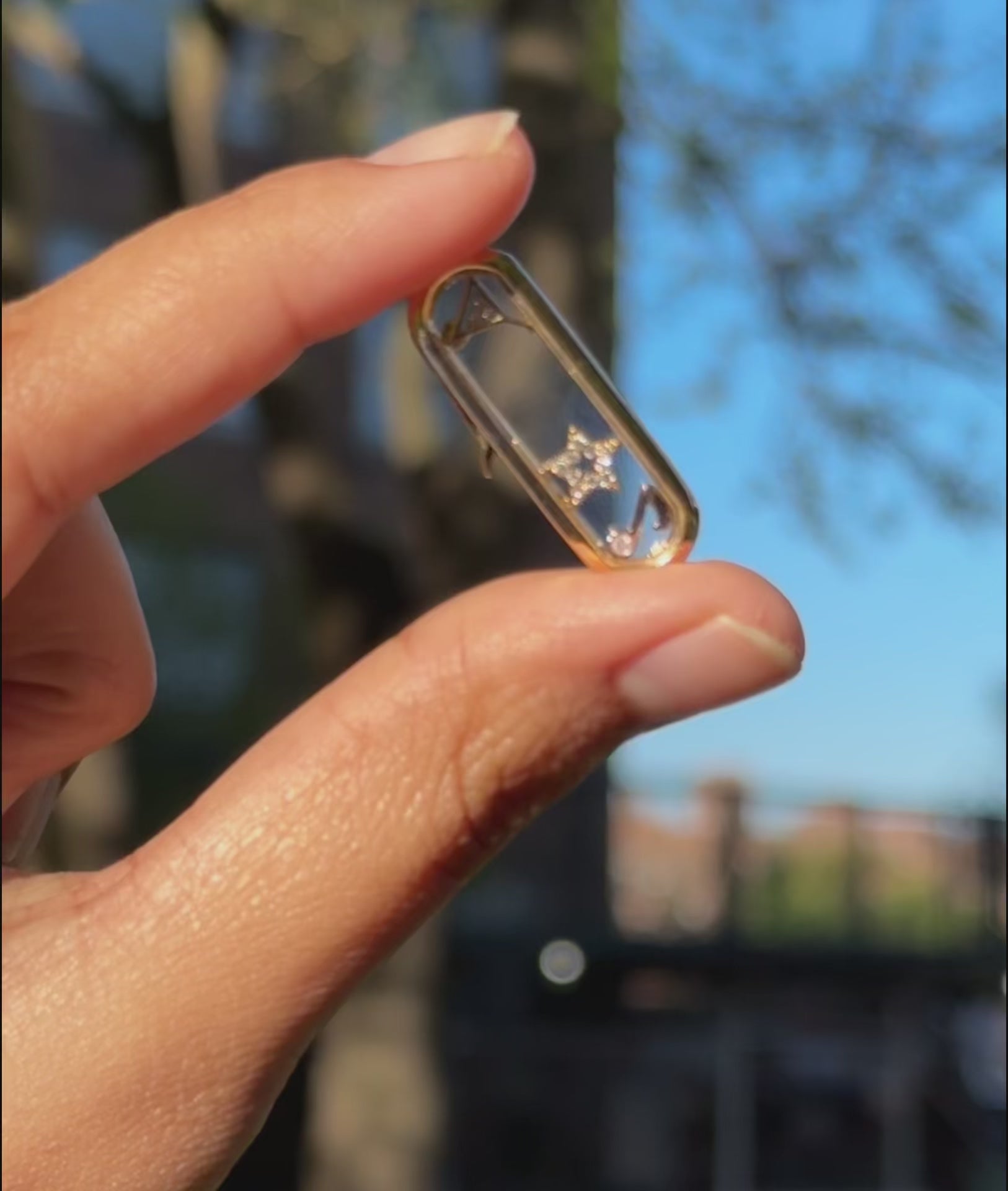Capsule glass locket charm styled with layered chains and mixed pendant shapes