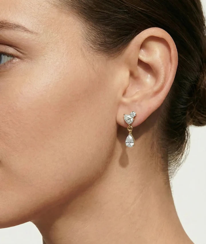 Model wearing three-stone diamond drop earrings in yellow gold