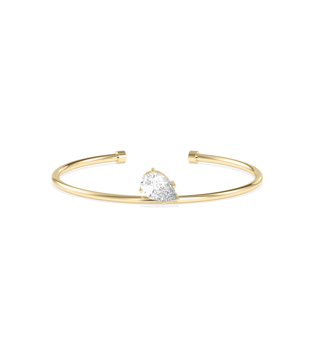 Yellow gold open cuff bracelet featuring a pear-shaped diamond solitaire in a prong setting